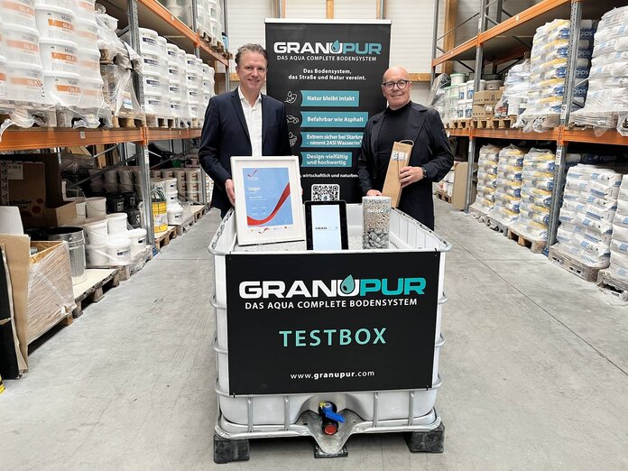 Rrene Schuch und Bürgermeister Georg Rosner stehen hinter der Testbox für Granupur in einer Lagerhalle