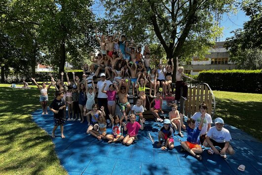 Die Kindersommer-Kinder haben sich bei einem Kletterfisch versammelt und für ein Foto mit dem Bürgermeister Aufstellung genommen.